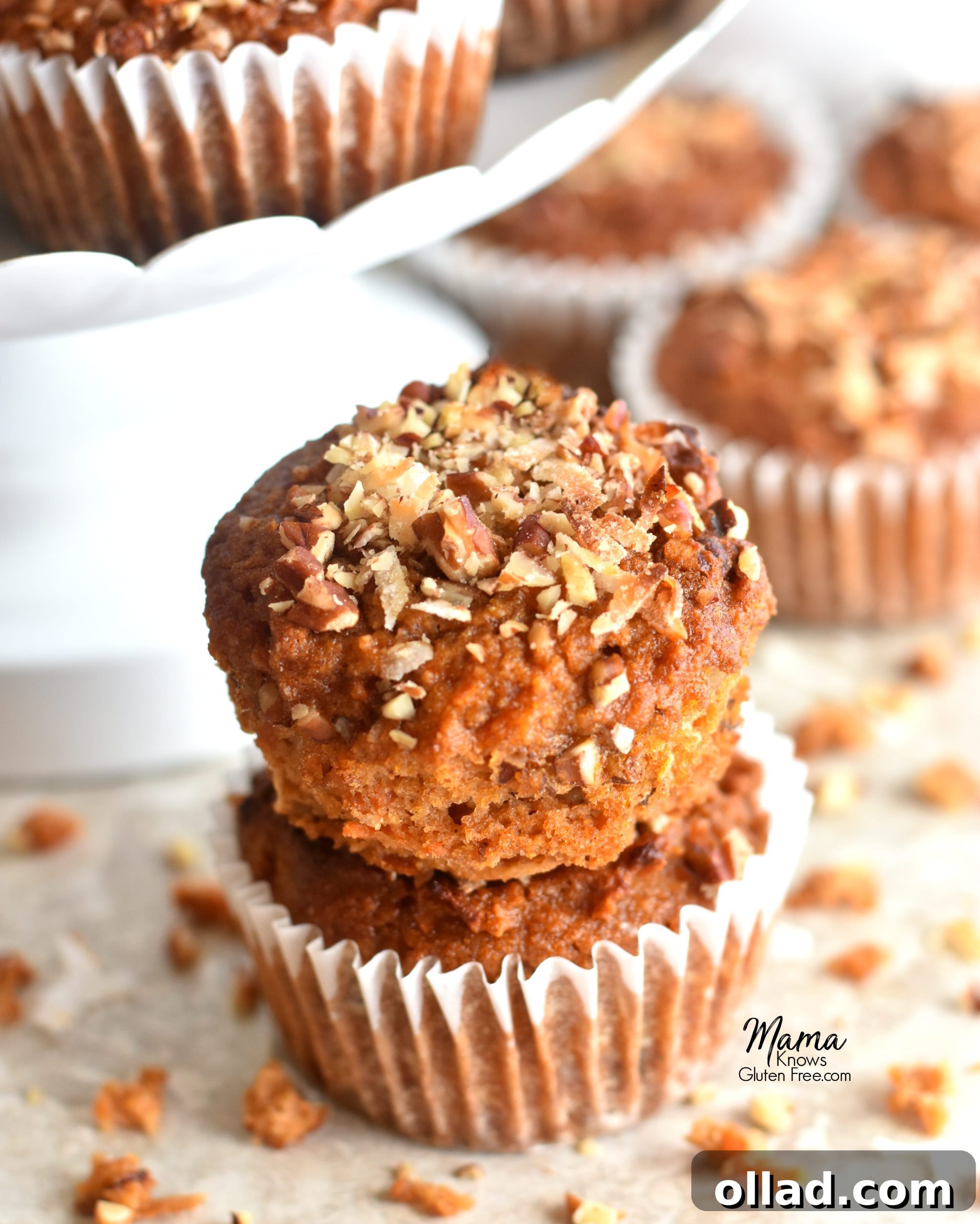 Paleo Carrot Cake Muffins Gluten Free Dairy Free Refined Sugar Free 2 Two perfectly baked Paleo carrot cake muffins stacked, with more delicious muffins blurred in the background, highlighting their moist texture and golden-brown tops.
