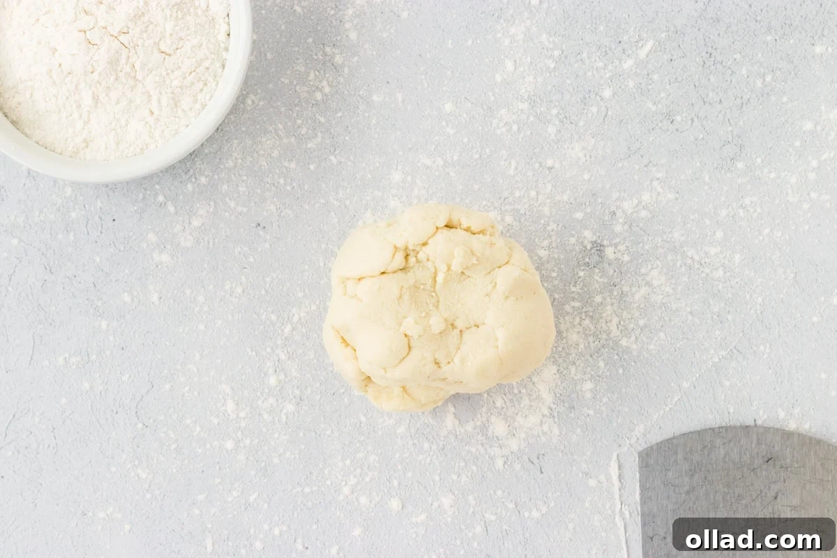 Pillowy Homemade Cauliflower Gnocchi 8 A perfectly round, smooth ball of cauliflower gnocchi dough resting on a lightly floured surface, glistening slightly and ready for the next stage of shaping. The texture looks pliable and uniform.