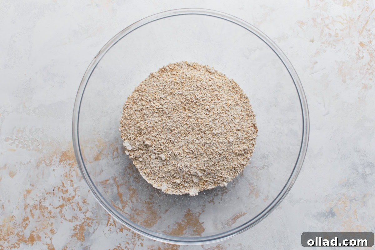 Wholesome Gluten-Free Banana Oat Loaf 5 A glass bowl filled with freshly blended oat flour, made from rolled oats, on a light textured surface.
