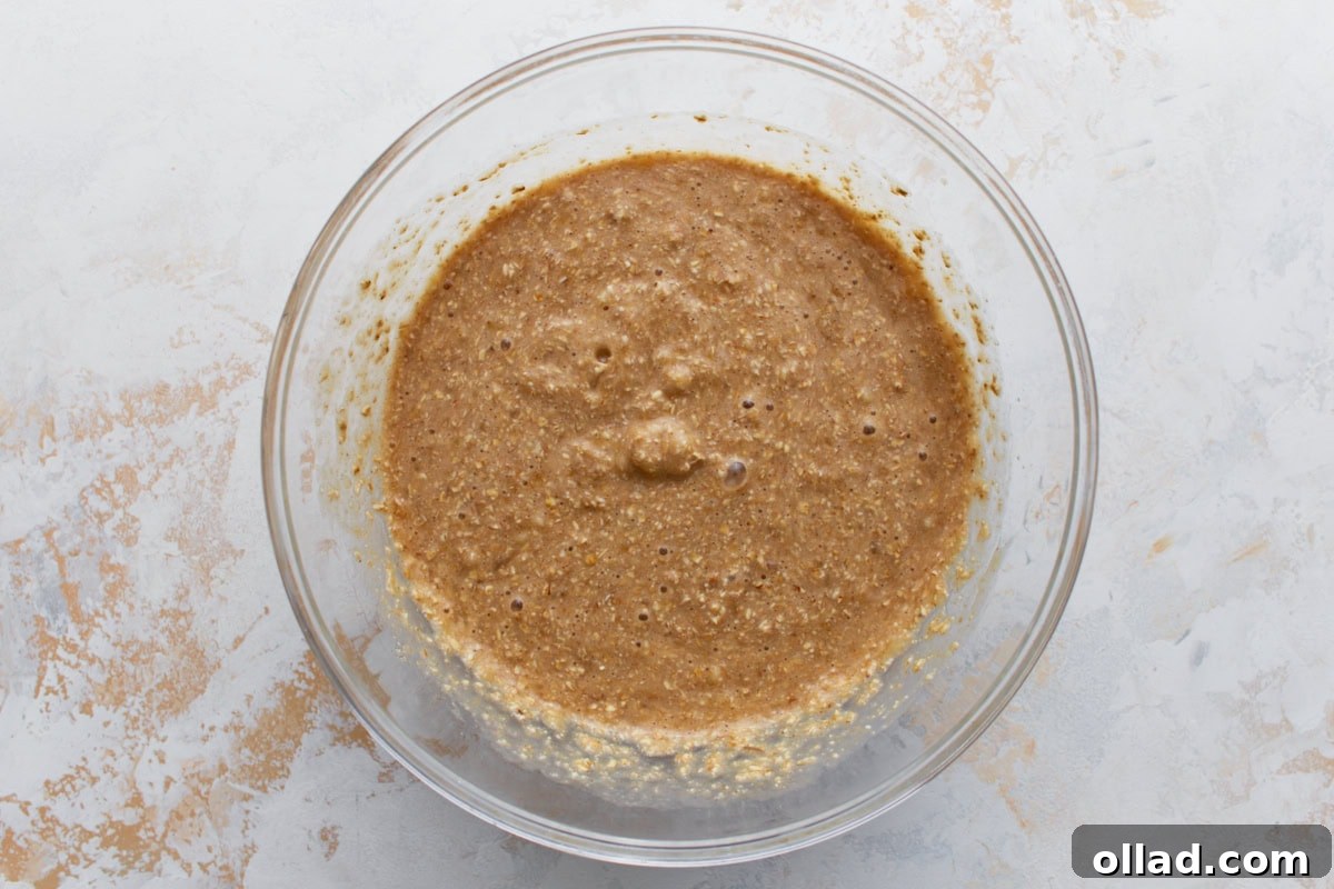 Wholesome Gluten-Free Banana Oat Loaf 7 A mixing bowl filled with wet banana bread batter, showing its thick, bubbly texture.