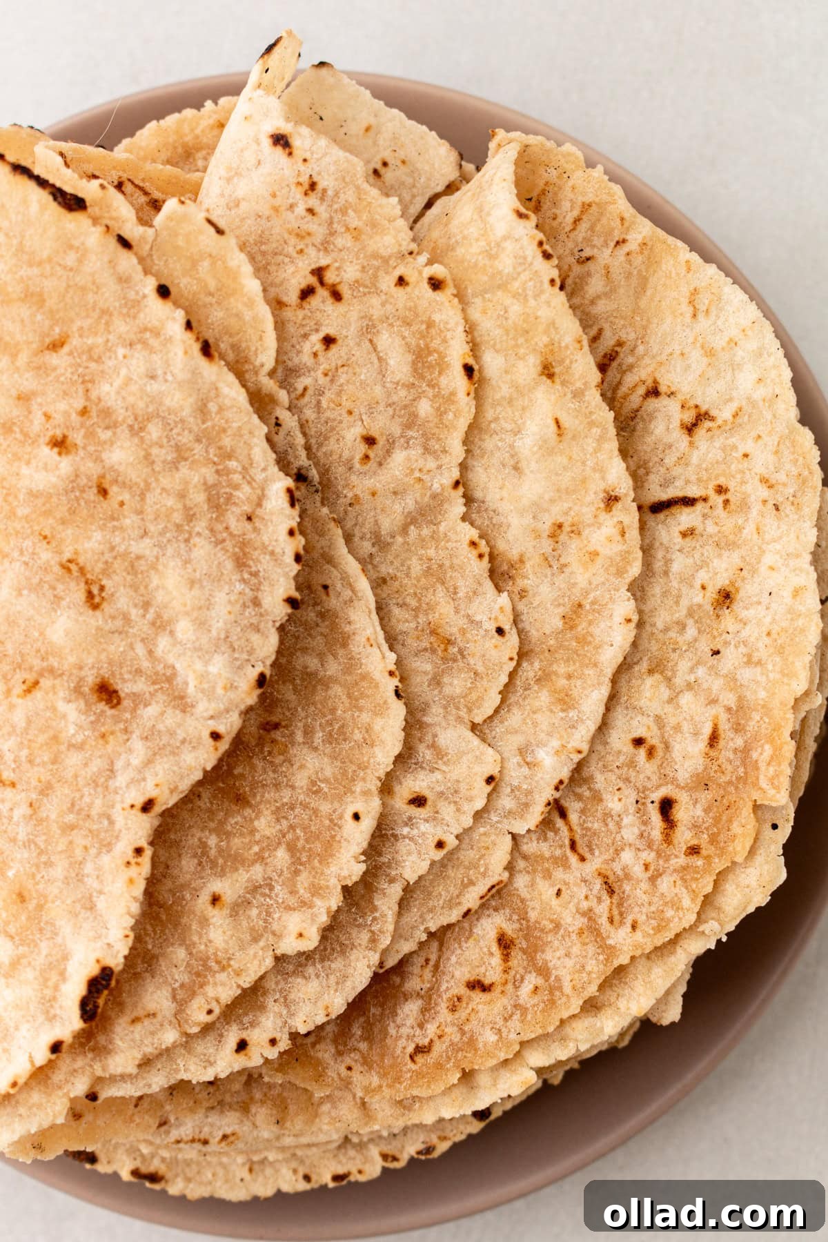 A stack of soft, golden-brown cassava flour tortillas on a plate, ready to be served, highlighting their inviting texture and rustic charm.