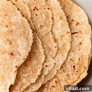A stack of cooked cassava flour tortillas on a plate, showing lightly browned and slightly crisped edges.
