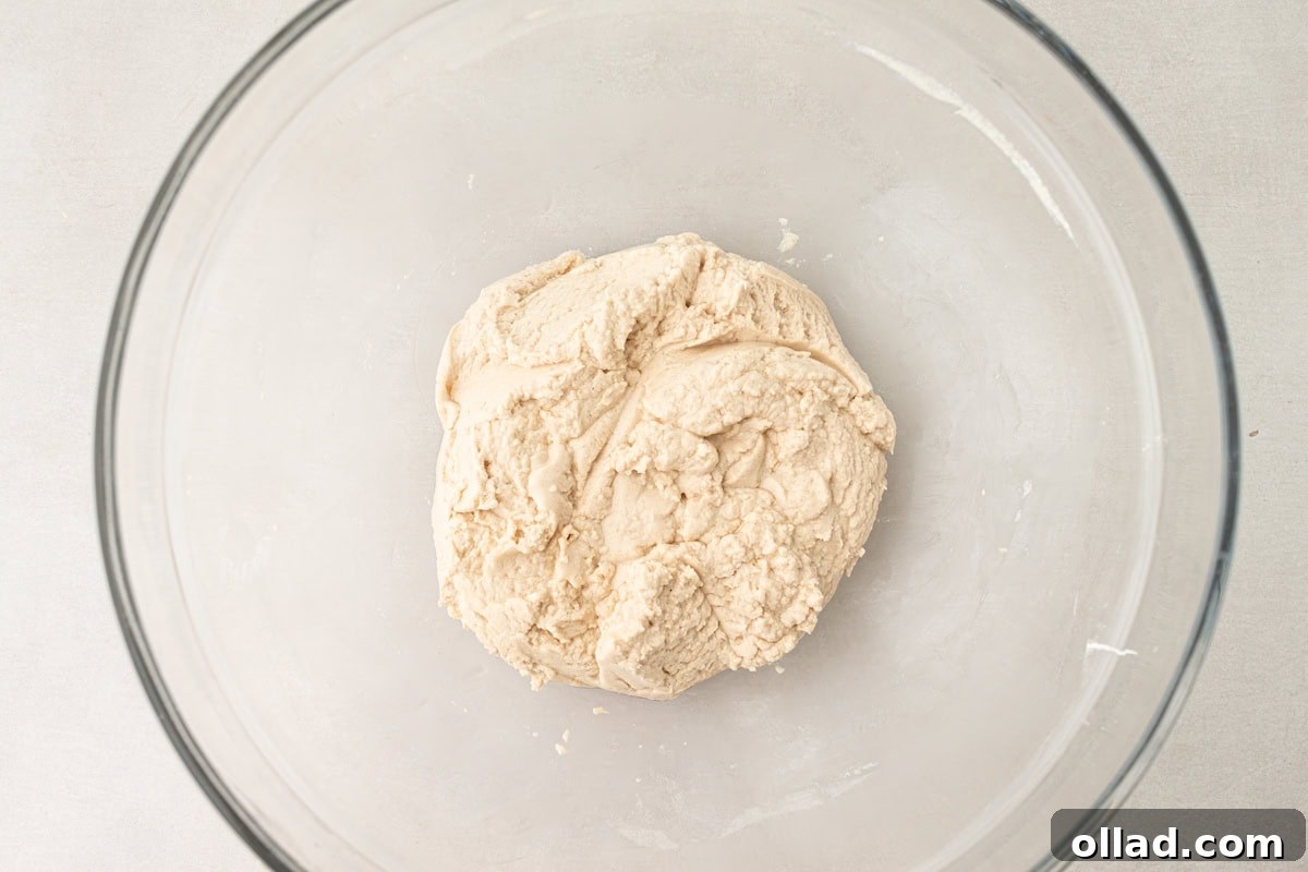 The cassava tortilla dough, expertly formed into a cohesive and smooth ball, rests inside a glass mixing bowl, ready for the next stage of preparation.