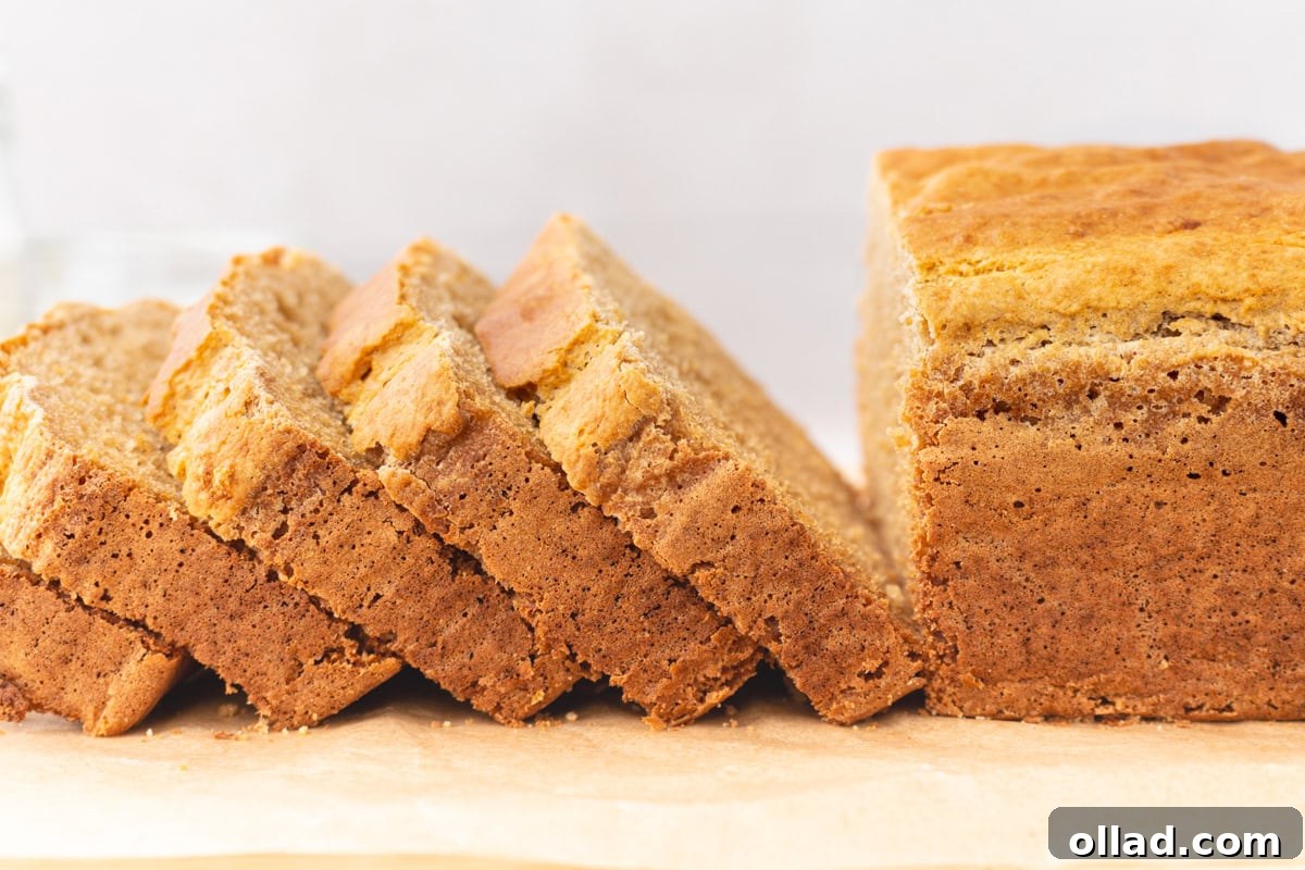 Yuca's Rustic Bake 10 A freshly baked and sliced loaf of cassava bread, resting on parchment paper, highlighting its crisp crust and soft, airy interior.