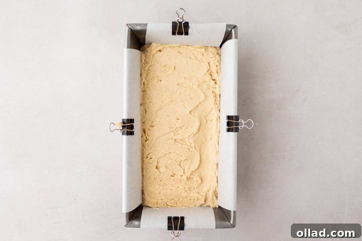 Yuca's Rustic Bake 8 Cassava bread batter evenly spread into a parchment-lined loaf pan, secured with clips on the sides.