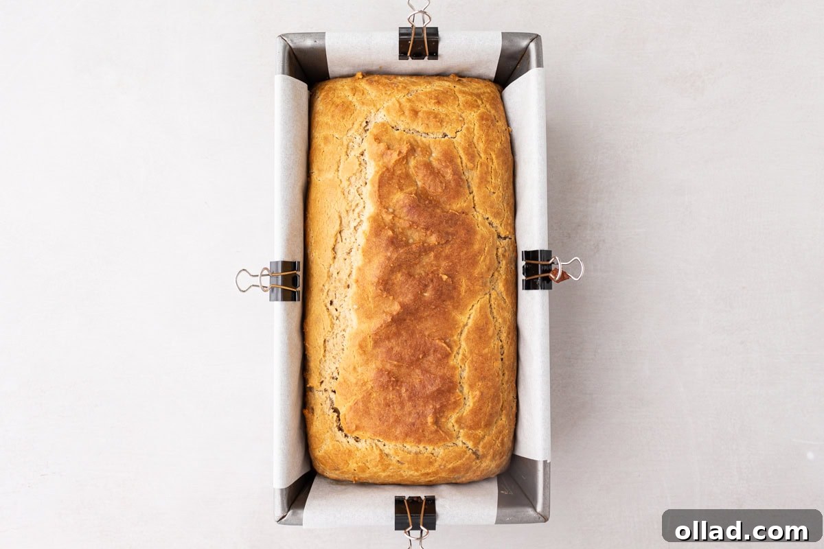 Yuca's Rustic Bake 9 A freshly baked loaf of golden-brown cassava bread, still in its parchment-lined pan, with firm edges and a perfect top.