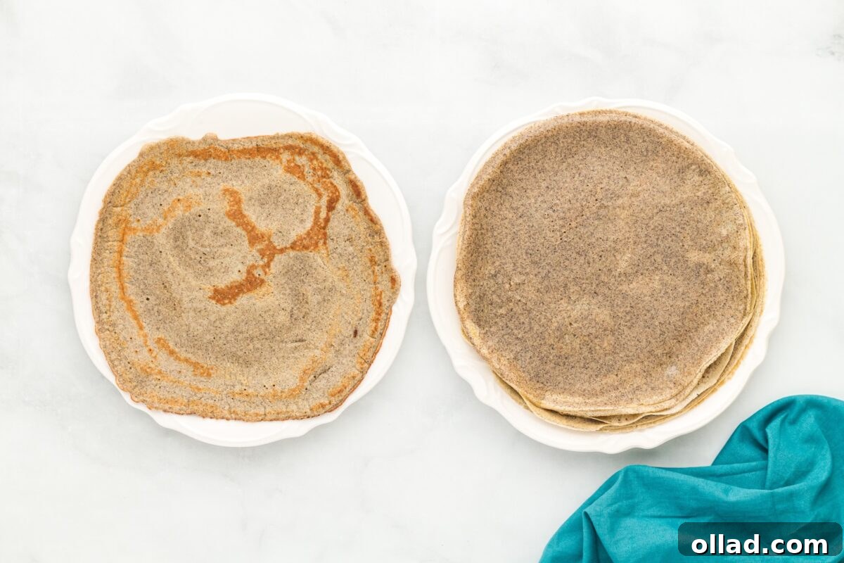 Buckwheat Galettes 10 Two white plates side by side—one with a stack of evenly cooked buckwheat crepes and the other with a single crepe showing darker browned spots.
