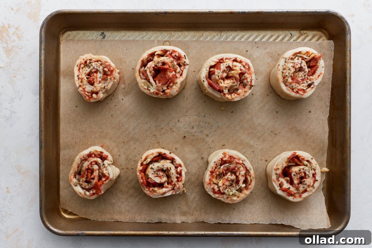 Irresistible Gluten-Free Pizza Poppers 11 Eight pizza rolls arranged on a parchment-lined baking sheet, ready for the oven.