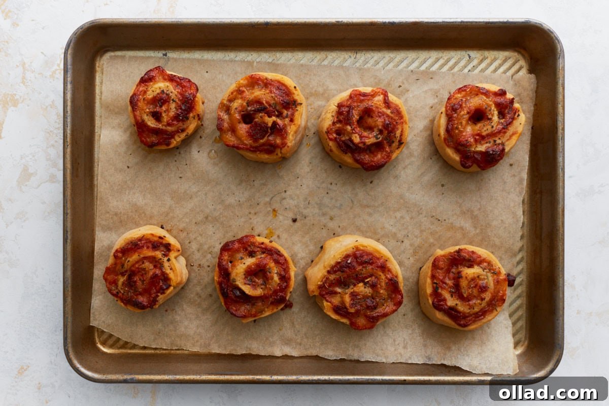 Irresistible Gluten-Free Pizza Poppers 12 baked pizza rolls on a cookie sheet