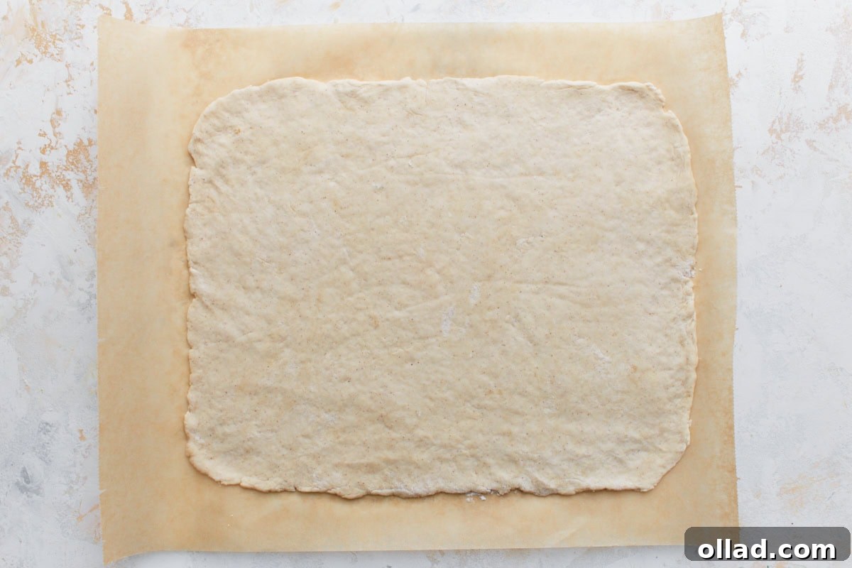 Irresistible Gluten-Free Pizza Poppers 6 Flattened gluten-free dough rolled into a large rectangle on parchment paper, ready for toppings.
