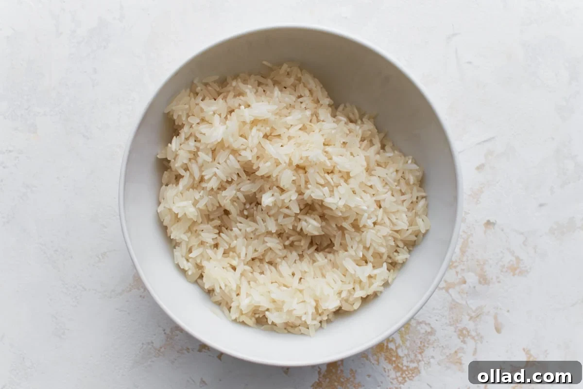 Flavorful Gluten-Free Rice Pilaf 5 A white bowl filled with rinsed, uncooked long-grain white rice set on a light-colored surface.