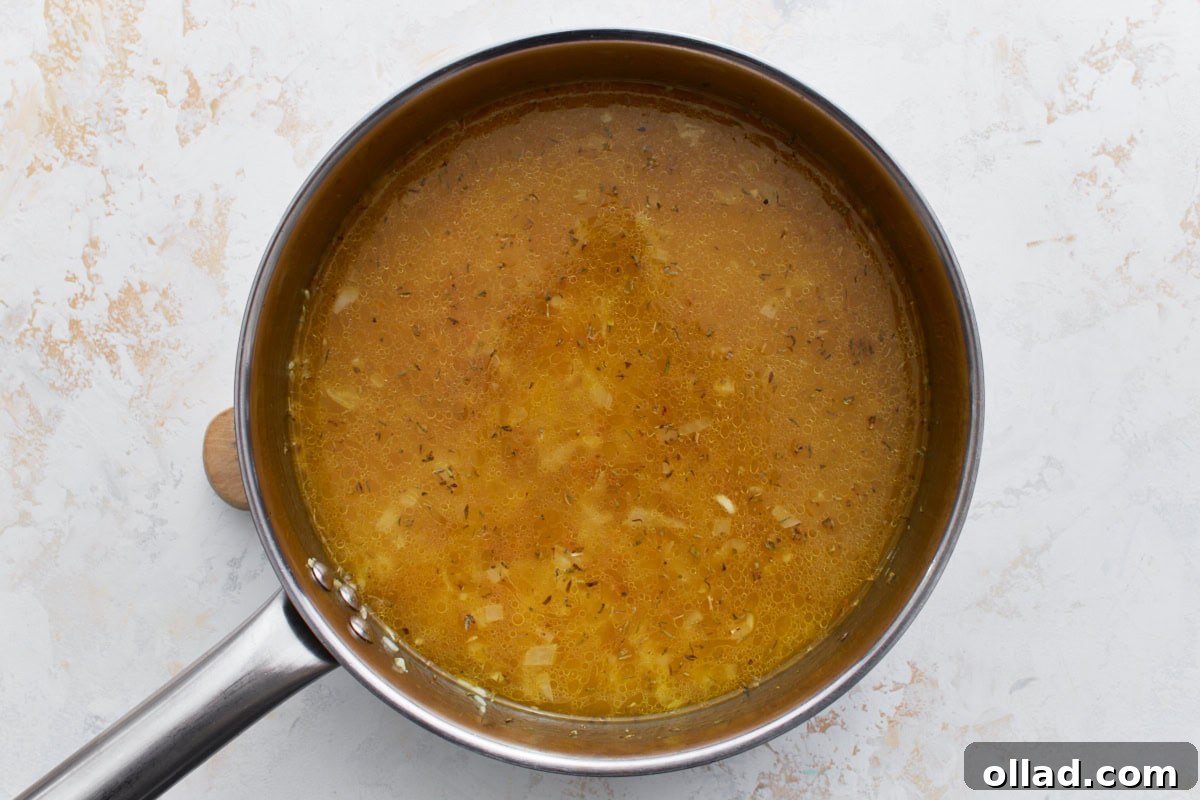 Flavorful Gluten-Free Rice Pilaf 9 Chicken broth and seasonings added to the pan with rice and pasta, starting to simmer.