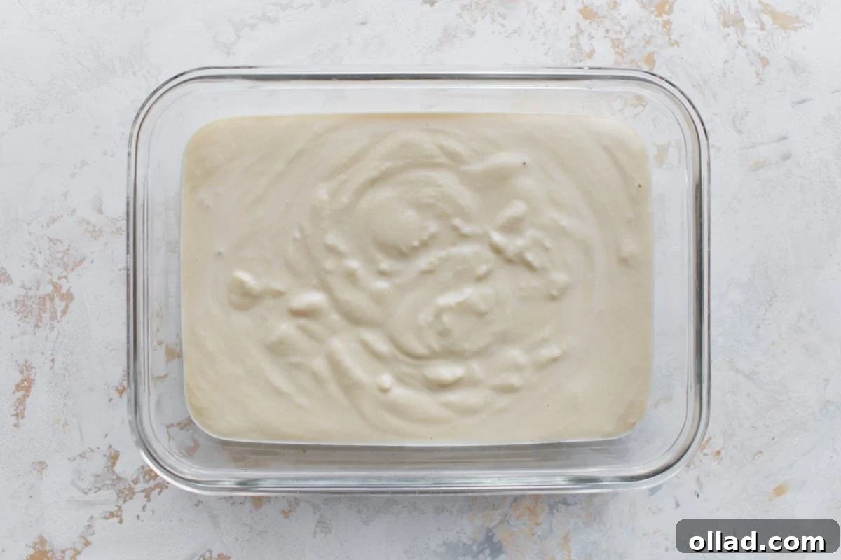 Glass container filled with freshly blended almond milk ice cream base, covered and ready for the freezer.