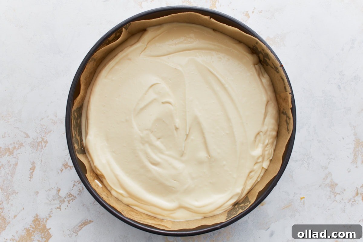 Unbaked cheesecake filling spread evenly over the crust in a springform pan.