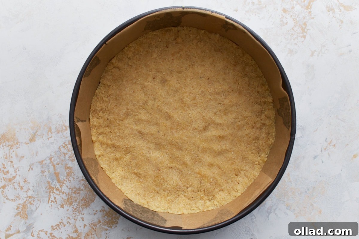 Unbaked almond flour crust pressed evenly into the bottom of a parchment-lined springform pan.