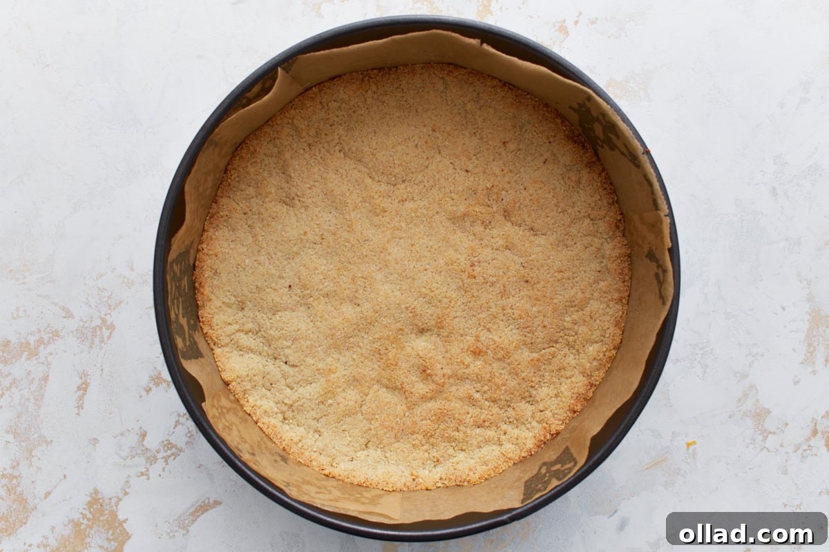 Golden-brown almond flour crust after baking, shown inside a parchment-lined springform pan.