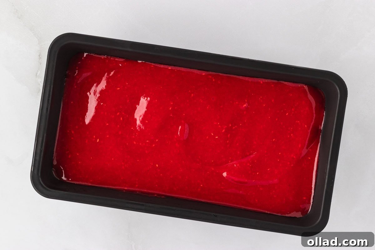 A black container holding the freshly blended raspberry sorbet mixture, glistening and ready to be placed into the freezer for solidification.