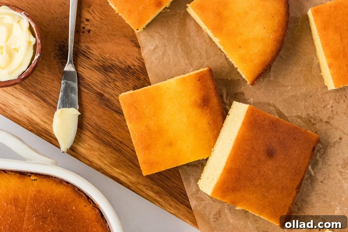 Ultimate Keto Cornbread 10 Cut squares of baked keto cornbread on a wooden board with butter on the side, ready to serve.
