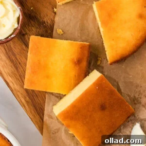 Ultimate Keto Cornbread 3 Overhead view of keto cornbread squares on parchment paper, golden brown with a small dish of butter and a butter knife nearby.