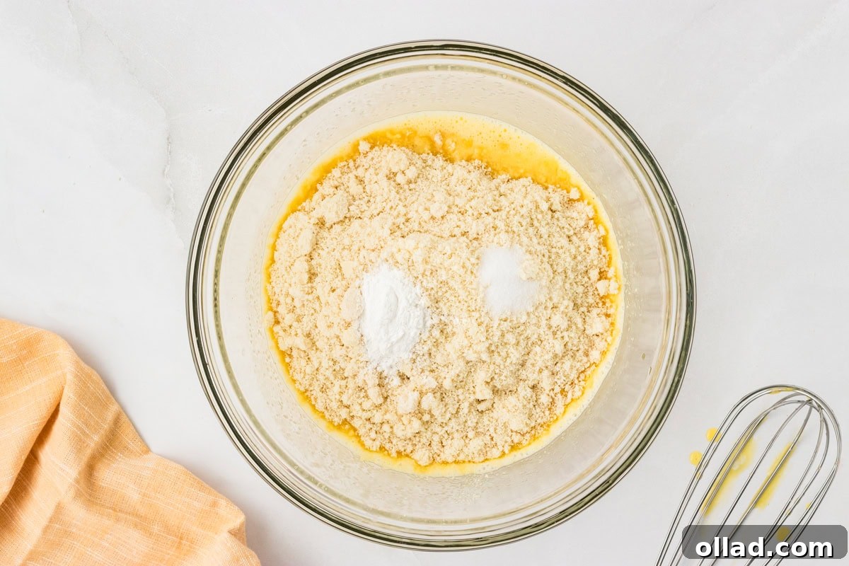 Ultimate Keto Cornbread 6 Bowl of wet ingredients topped with almond flour, baking powder, and salt before mixing, ready to combine.