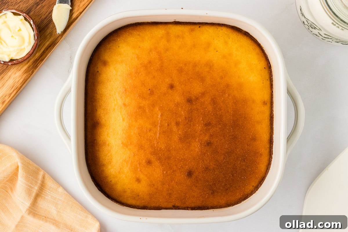 Ultimate Keto Cornbread 9 Freshly baked keto cornbread in a white square baking dish, golden brown on top.