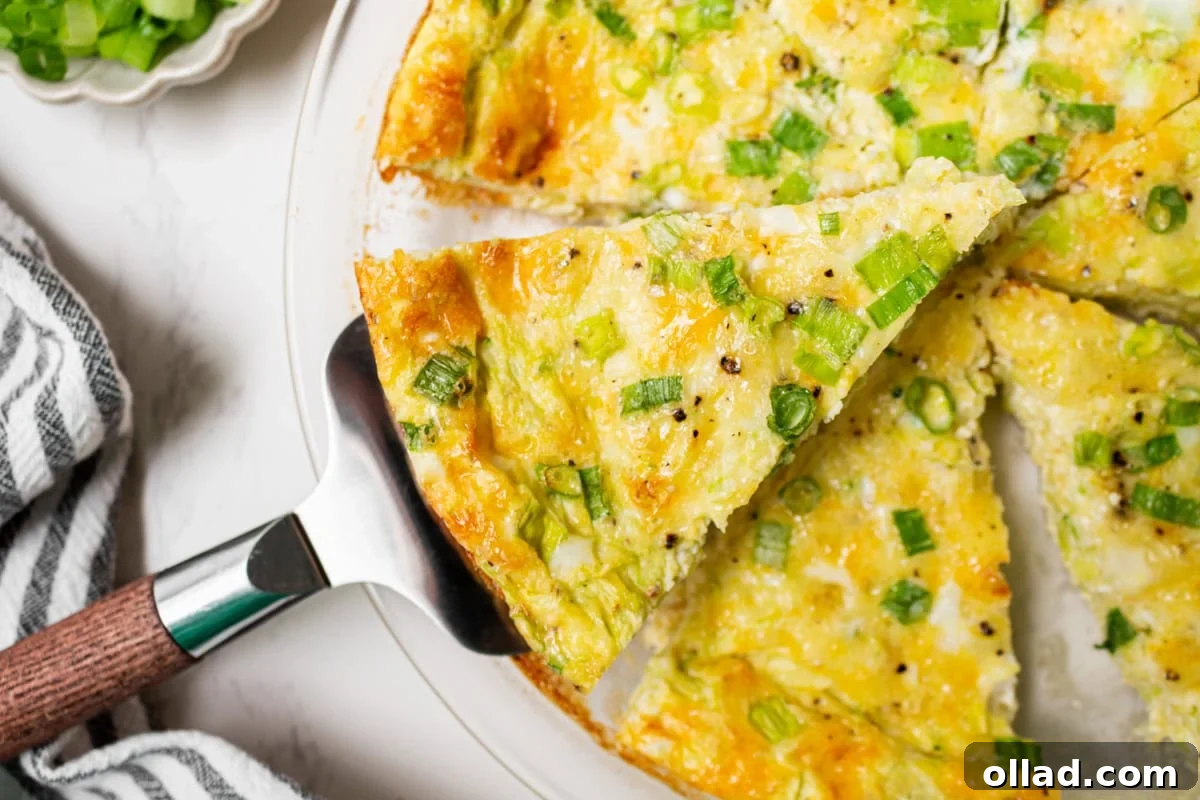 A skilled hand gently lifts a perfect, golden-brown slice of crustless zucchini quiche from the baking dish using a gleaming metal pie server, highlighting its firm, yet tender texture.
