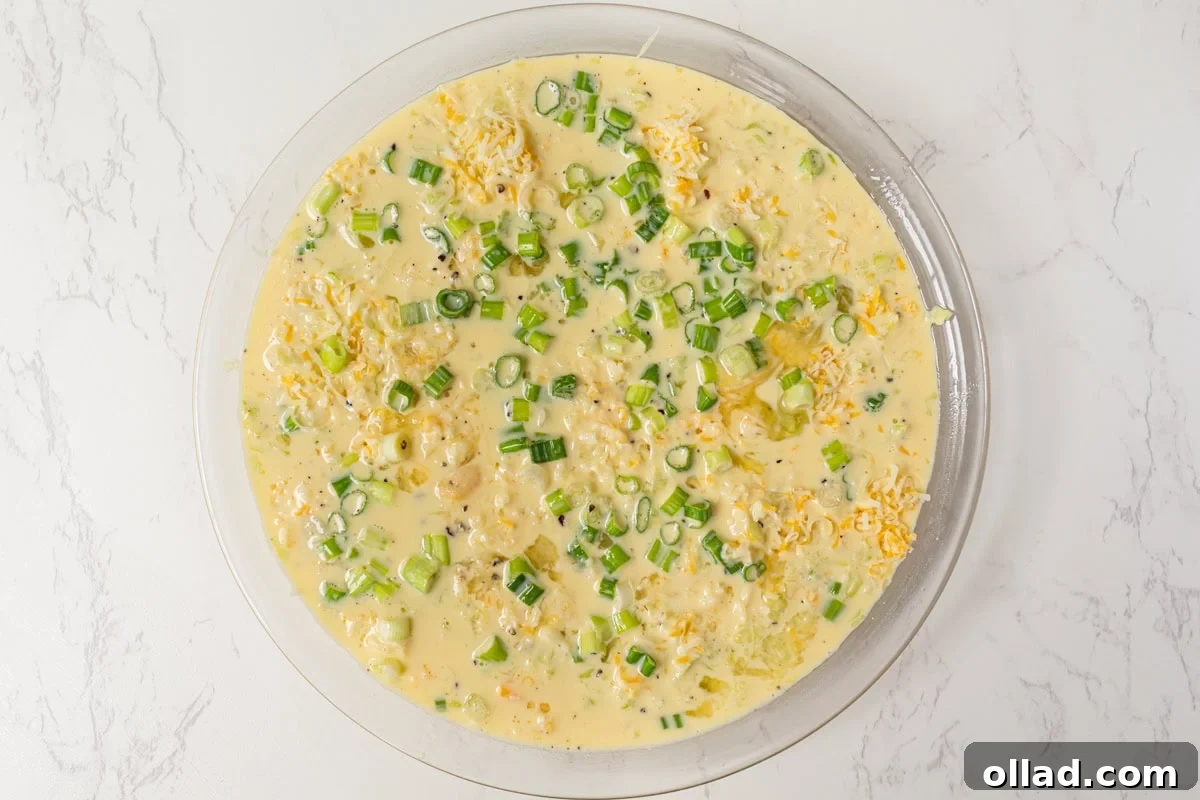 The assembled crustless zucchini quiche, beautifully presented in a pie dish, with the rich egg and cheese mixture poured over the carefully layered vegetable base, garnished and poised for the oven.