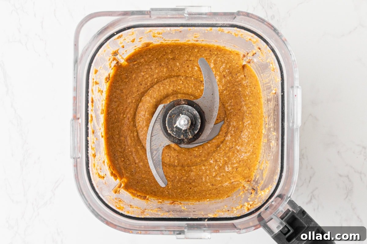Pumpkin, almond butter, eggs, and maple syrup blended into a smooth orange batter base for flourless pumpkin muffins.