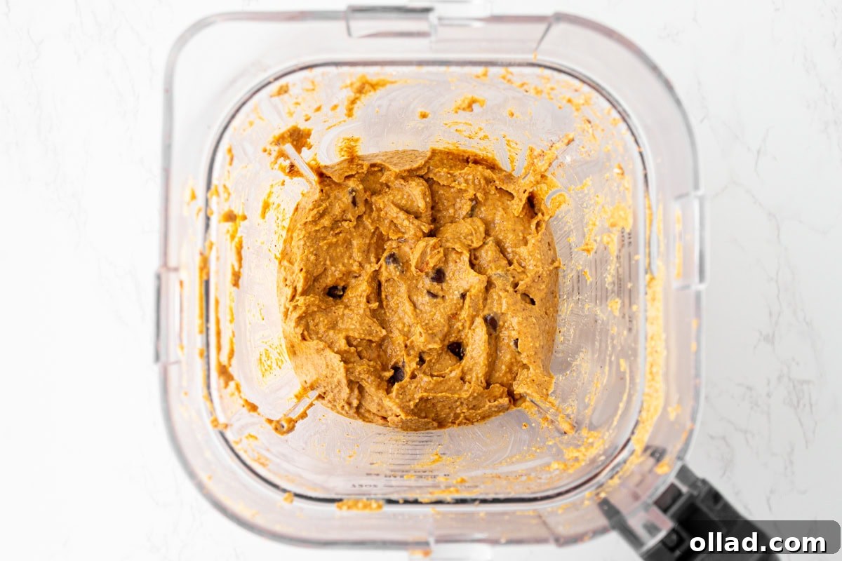 Pumpkin muffin batter fully blended with chocolate chips stirred in, thick and creamy in the blender bowl.