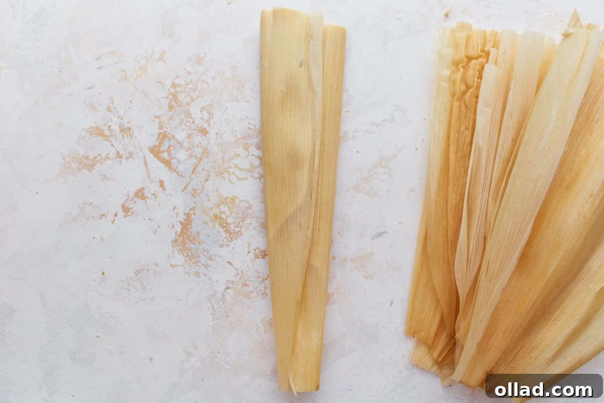 A filled tamale neatly folded and ready for steaming, with extra husks stacked beside it.