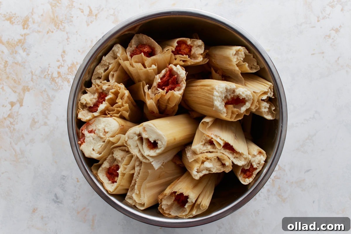 Filled tamales arranged upright in a pot with open ends facing up, ready to be steamed.