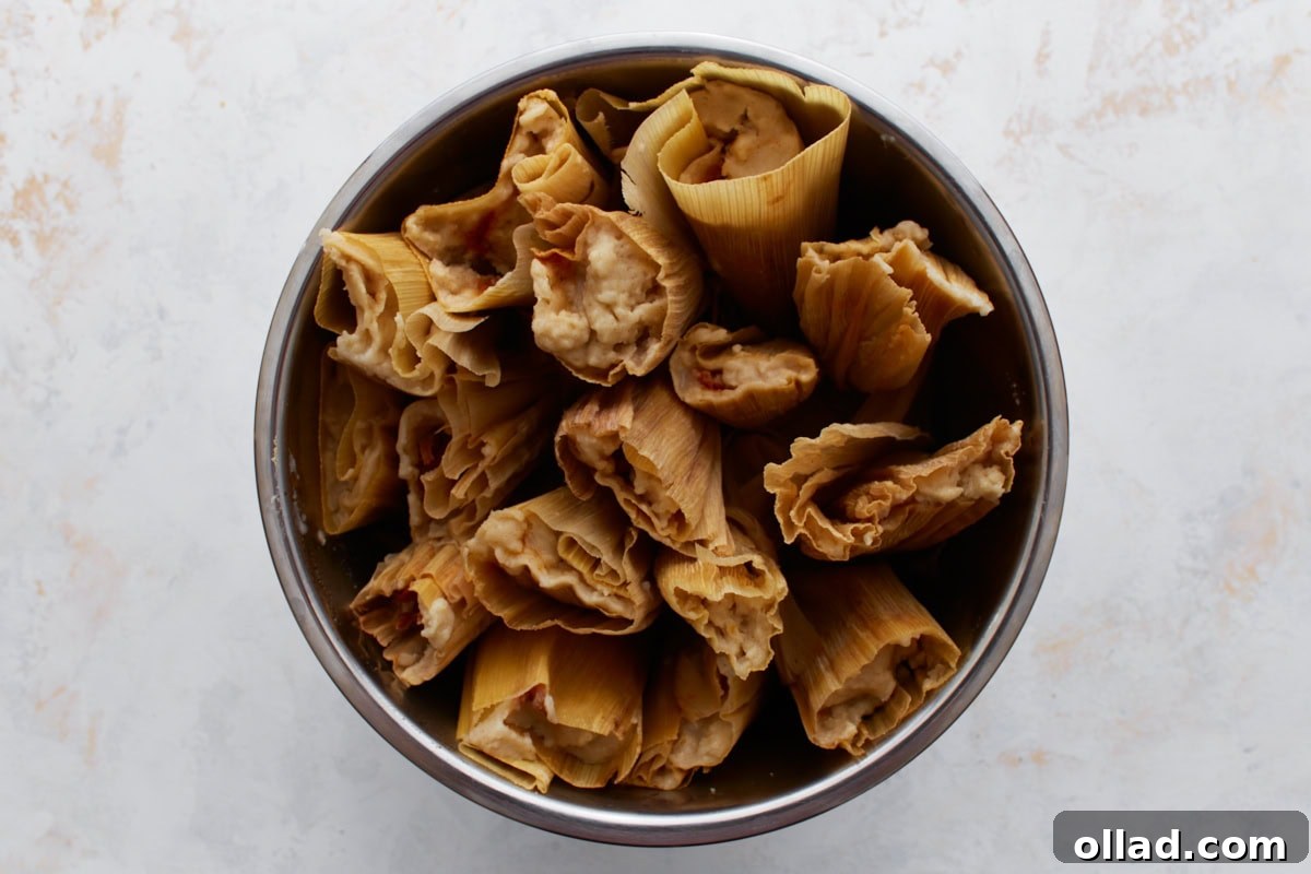 Fully cooked tamales after steaming, with golden husks and firm masa showing at the tops.