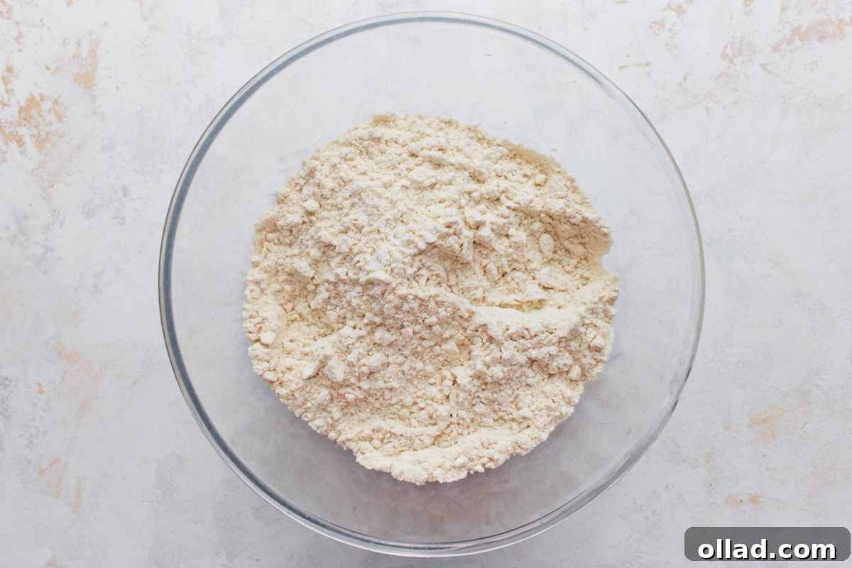 A glass bowl filled with masa harina, baking powder, and salt mixed together for the tamale dough.