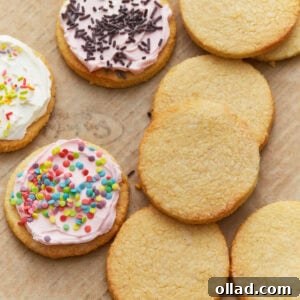 Frosted and unfrosted almond flour sugar cookies arranged on a parchment-lined baking sheet.