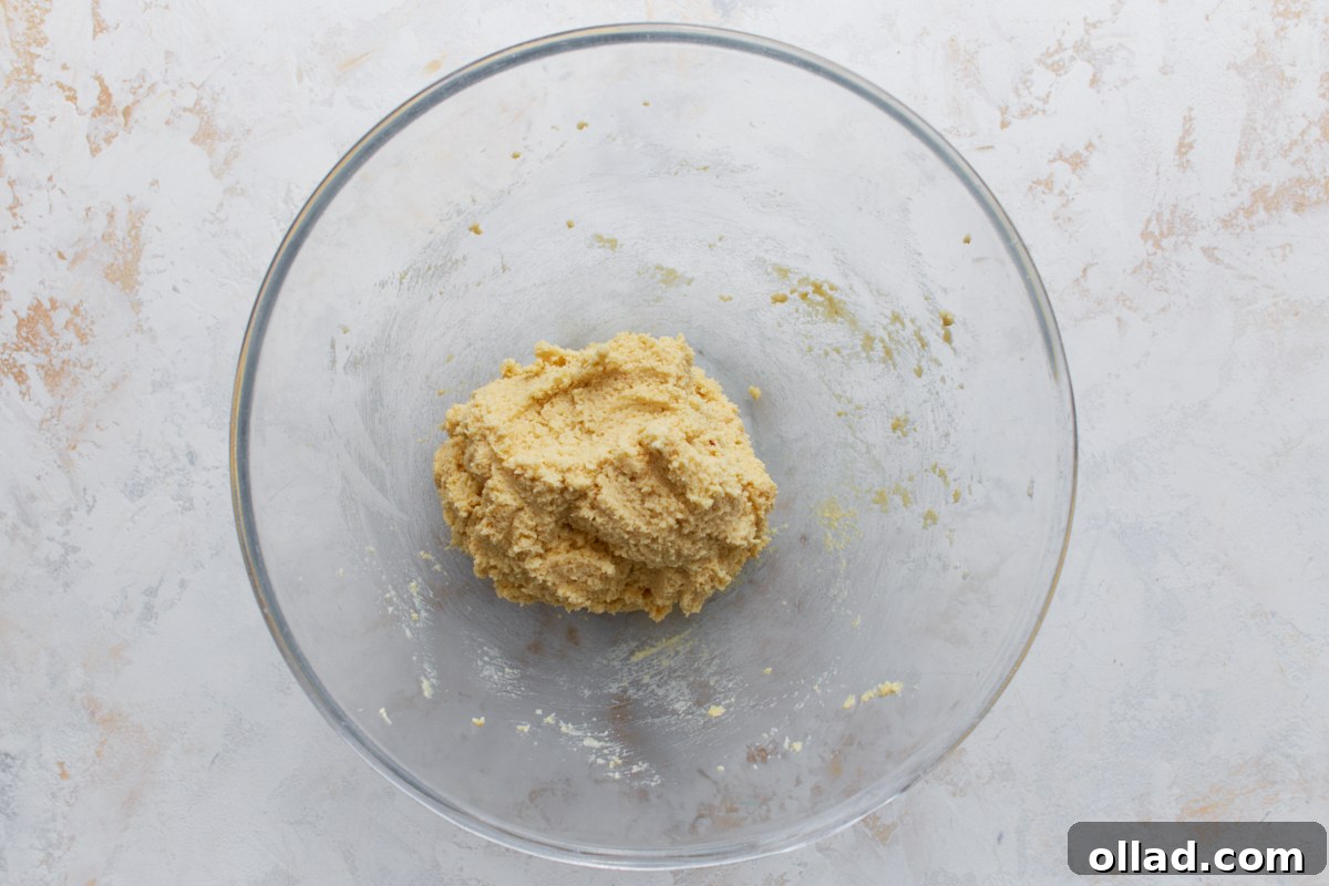 Almond flour sugar cookie dough combined and formed into a soft ball in a glass bowl.