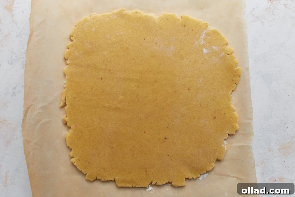 Chilled almond flour sugar cookie dough rolled out between parchment paper.