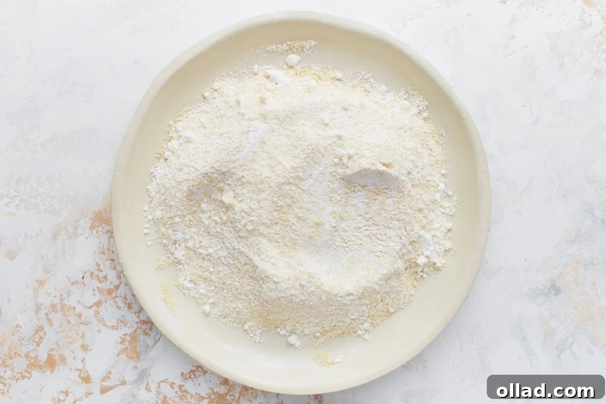Irresistible Gluten-Free French Macarons 5 A wide, shallow plate filled with the double-sifted mixture of almond flour and powdered sugar, essential for a smooth macaron batter.