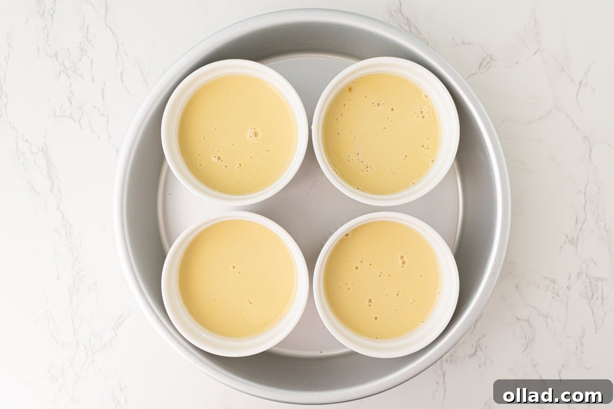 Dairy-free custard evenly poured into ramekins set inside a baking dish.