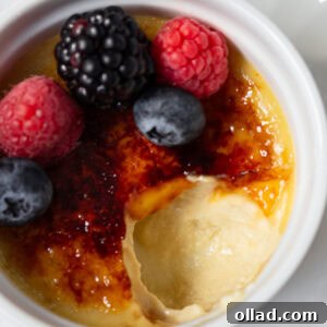 Dairy-free crème brûlée with a crackly caramelized sugar top, garnished with fresh berries in a white ramekin.