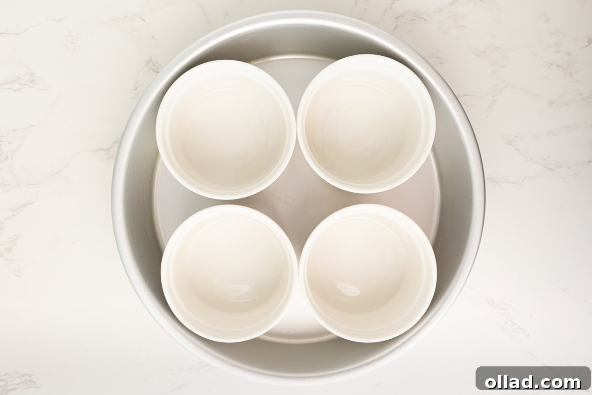 Four empty white ramekins arranged in a round baking dish
