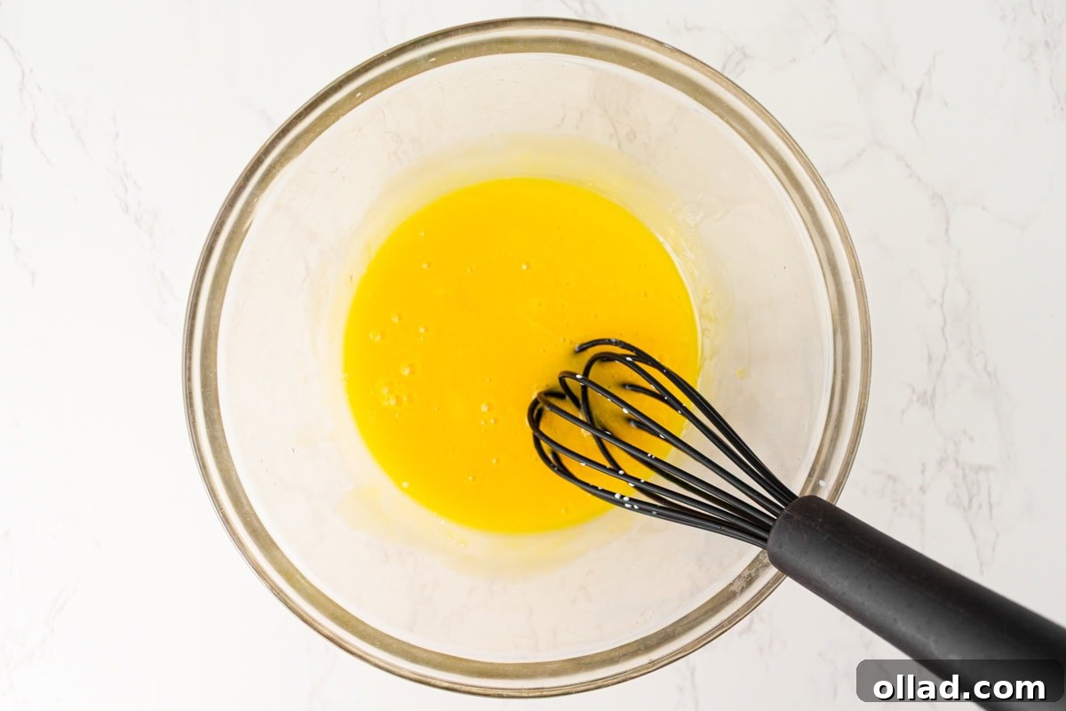 Egg yolks being whisked in a glass bowl for dairy-free crème brûlée.