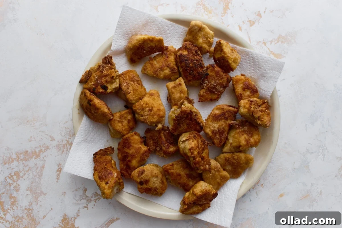 Crispy gluten-free fried chicken pieces resting on paper towels after shallow frying