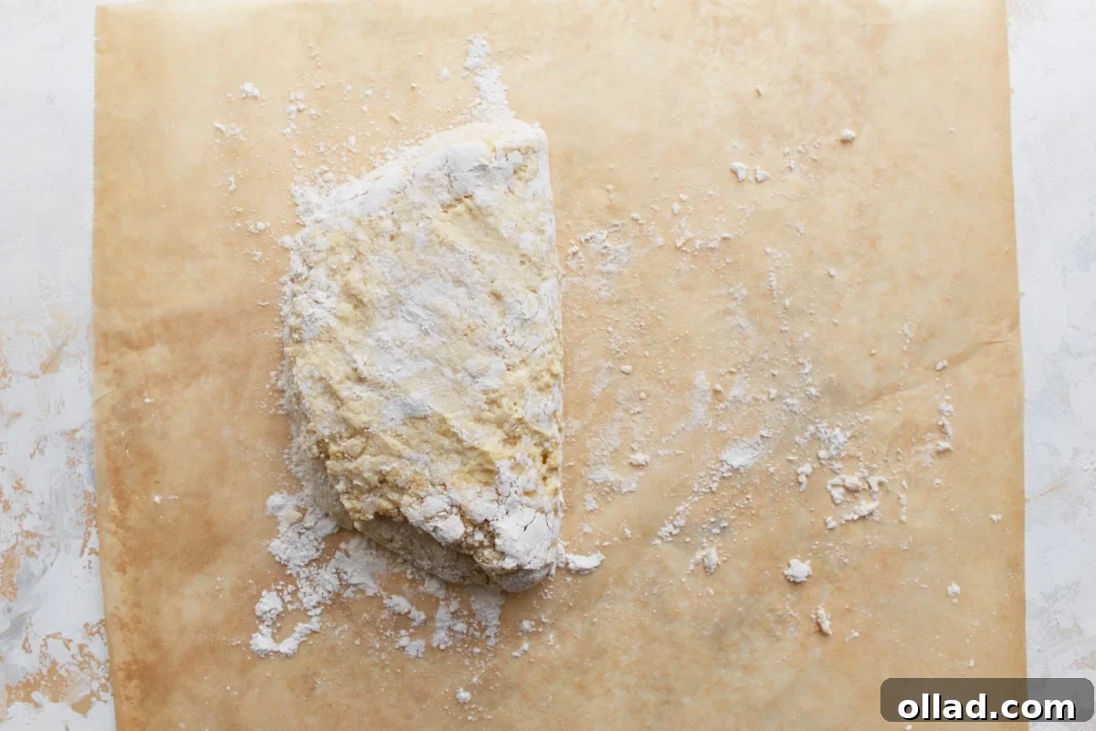 Biscuit dough being carefully folded over on itself, illustrating the technique used to create multiple flaky layers before the biscuits are cut.