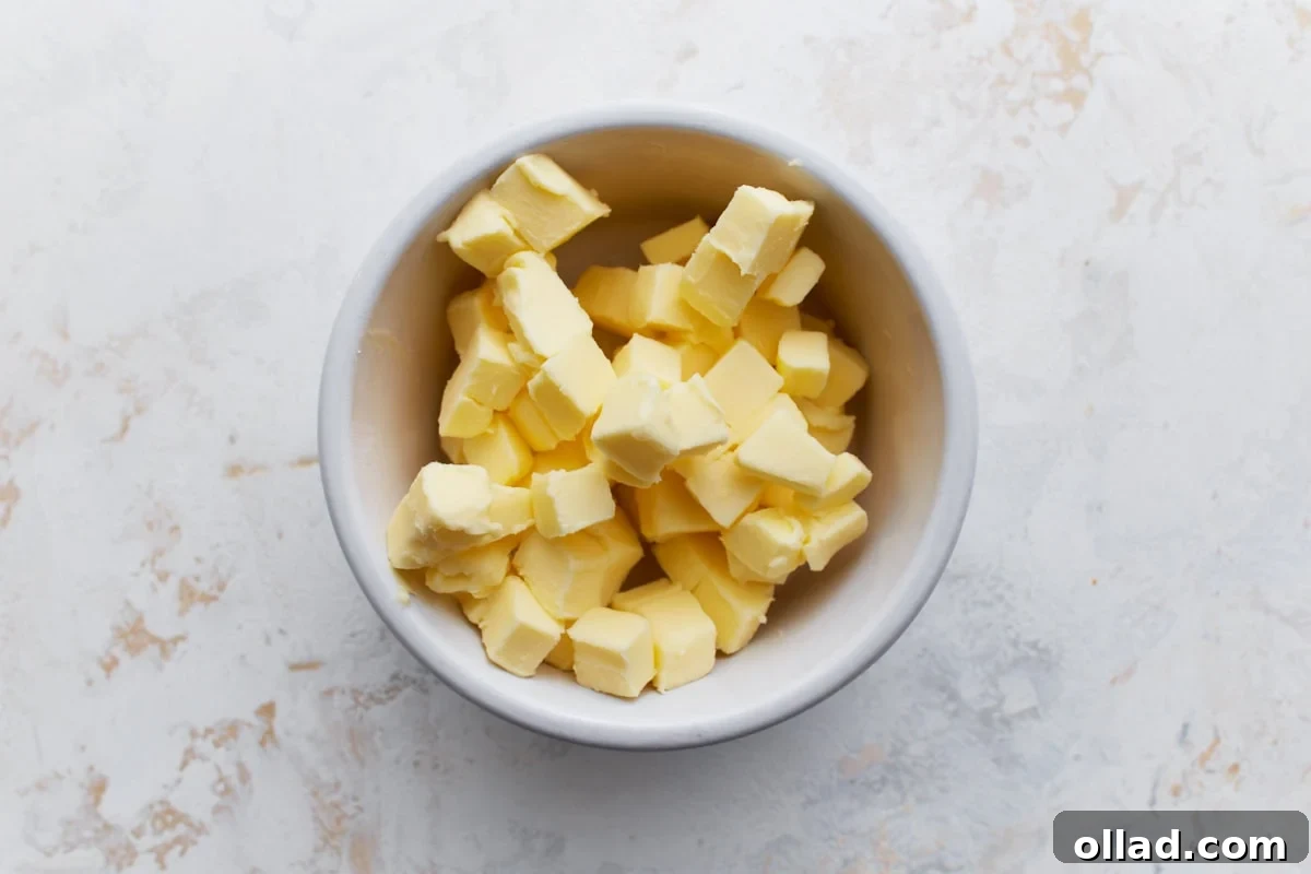 A white bowl filled with small cubes of cold butter, perfectly prepped to be mixed into the biscuit dough, highlighting its crucial cold temperature for flakiness.