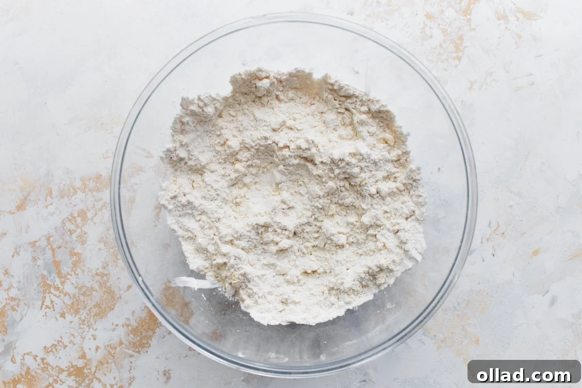 A clear mixing bowl holding dry ingredients, perfectly blended and ready for the next step in making biscuit dough, showcasing a smooth, uniform mixture.