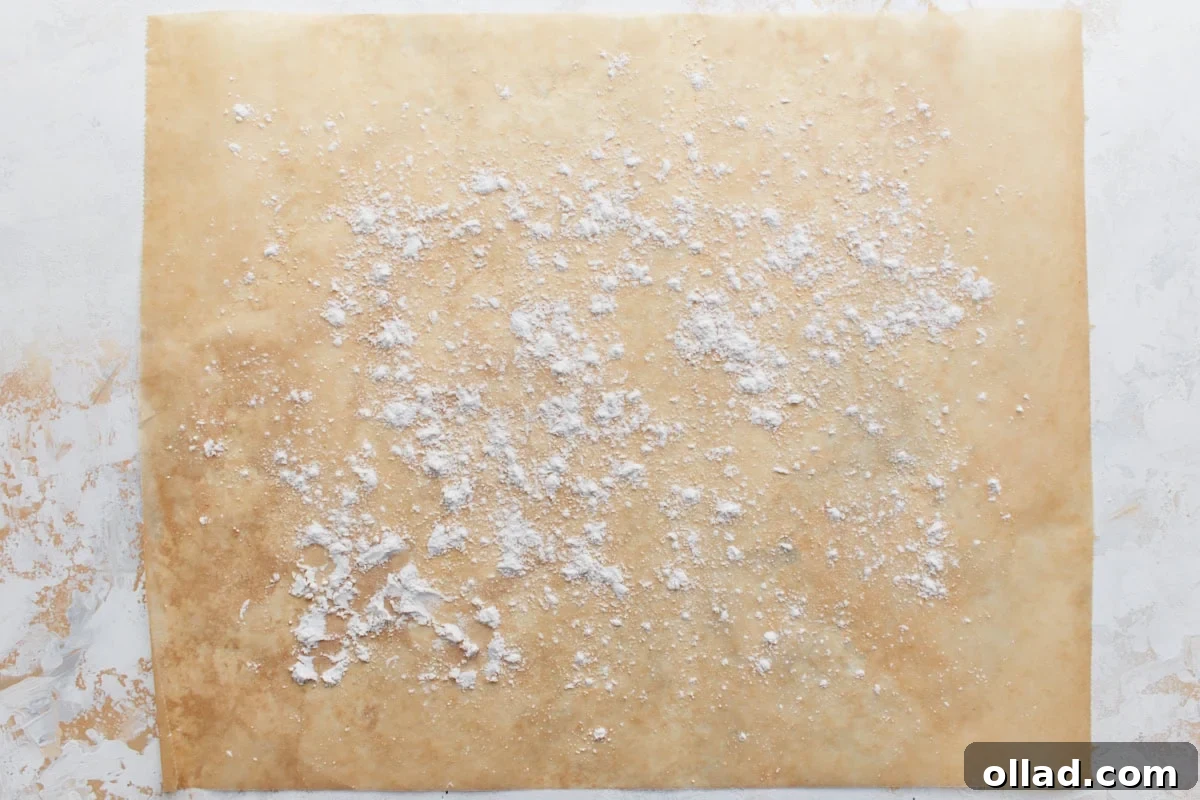 Parchment paper lightly dusted with gluten-free flour, ready as a non-stick surface for shaping biscuit dough, emphasizing proper preparation.