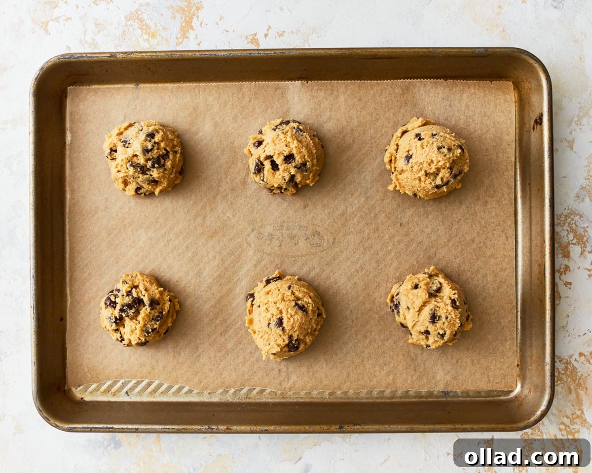 Gluten-free chocolate chip cookie dough balls on a parchment linked baking sheet.