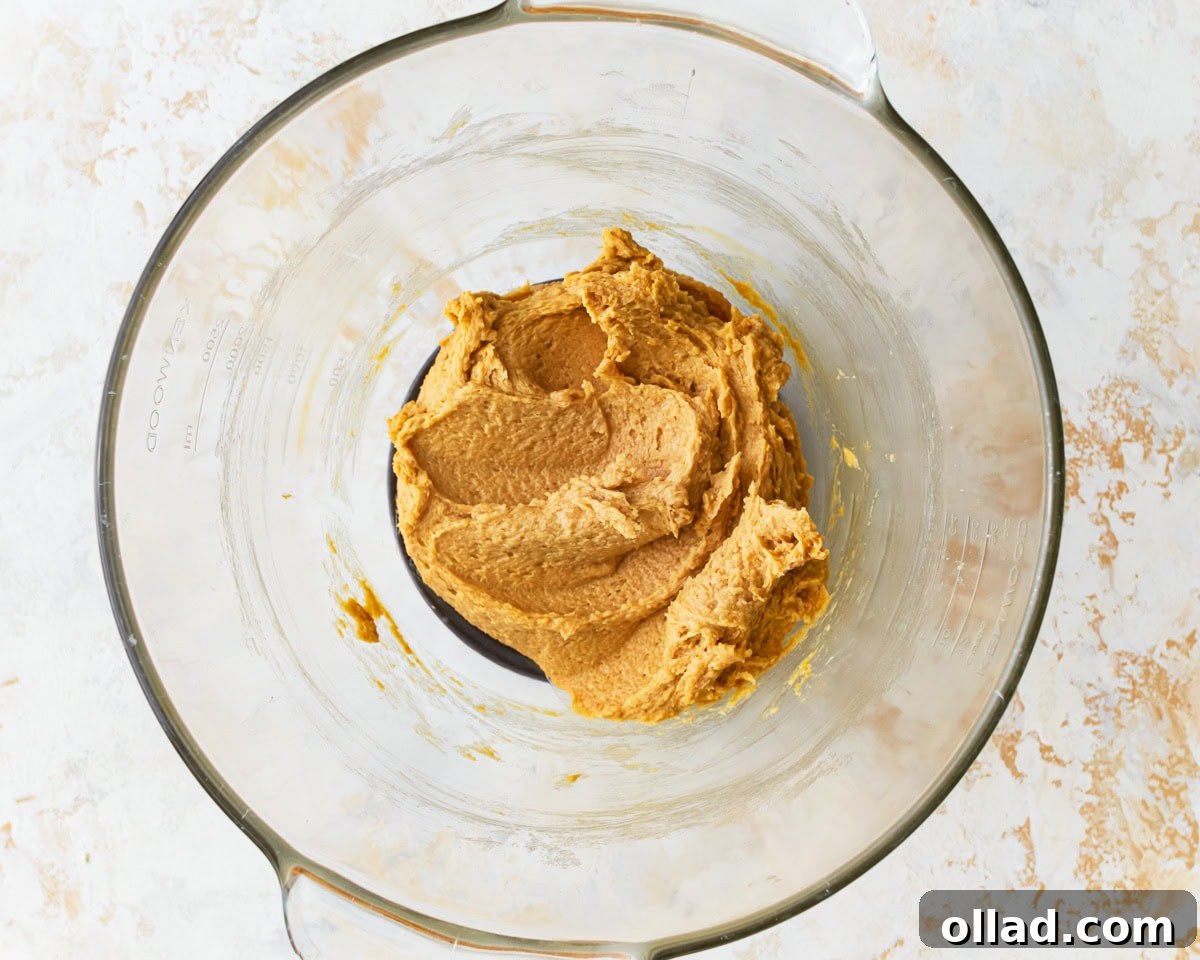 Butter and sugar mixture combined with egg and molasses in for gluten-free chocolate chip cookies in a glass mixing bowl