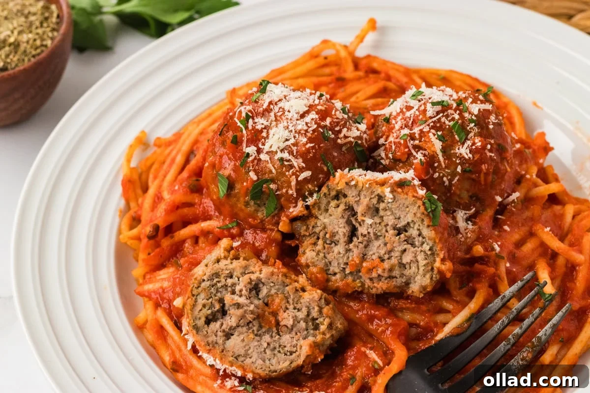 Delicious Gluten-Free Meatballs 13 A plate of spaghetti topped with marinara sauce and three gluten-free meatballs, one cut open to show the juicy, tender center. Sprinkled with grated Parmesan and chopped parsley.