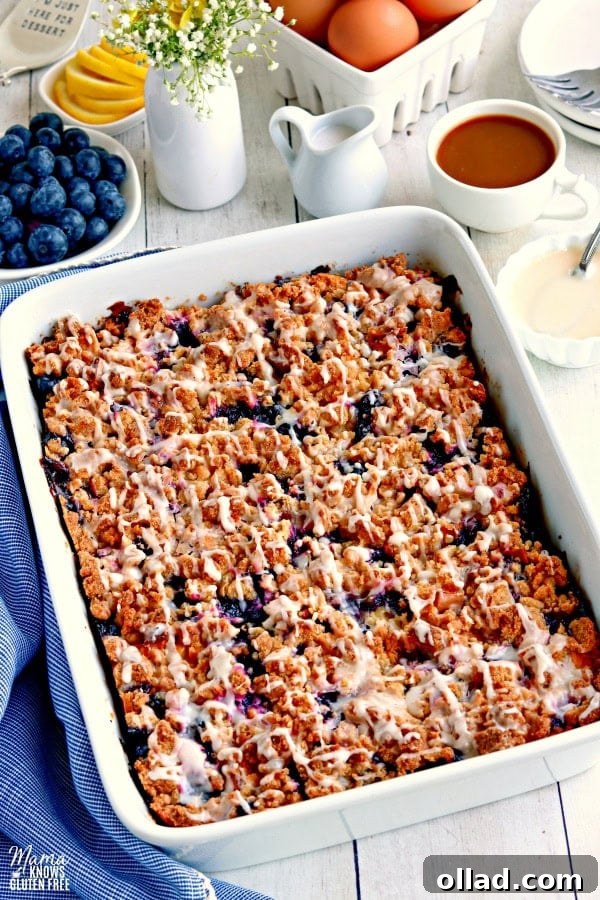 A beautifully baked gluten-free blueberry lemon breakfast casserole in a pan, surrounded by fresh blueberries, lemons, coffee, cream, and delicate flowers, ready to be served for a delightful breakfast.
